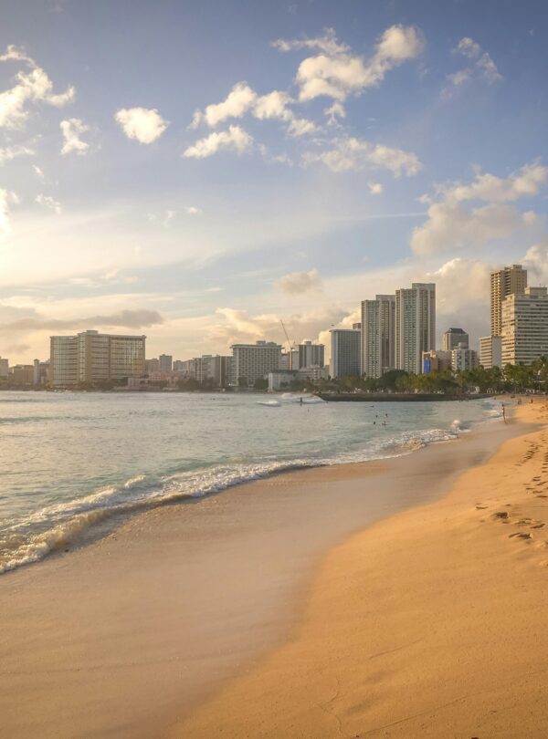 Experience the serene beauty of Honolulu's beach at sunset, featuring the city's stunning skyline.