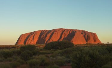 Capture the majestic Uluru rock formation glowing under the sunset. A natural wonder in Australia's Outback.