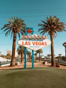 Capture of the famous Welcome to Las Vegas sign surrounded by palm trees under a clear blue sky.