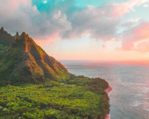 Breathtaking view of Kauai's lush greenery and ocean at sunset, with vibrant colors and dramatic landscapes.