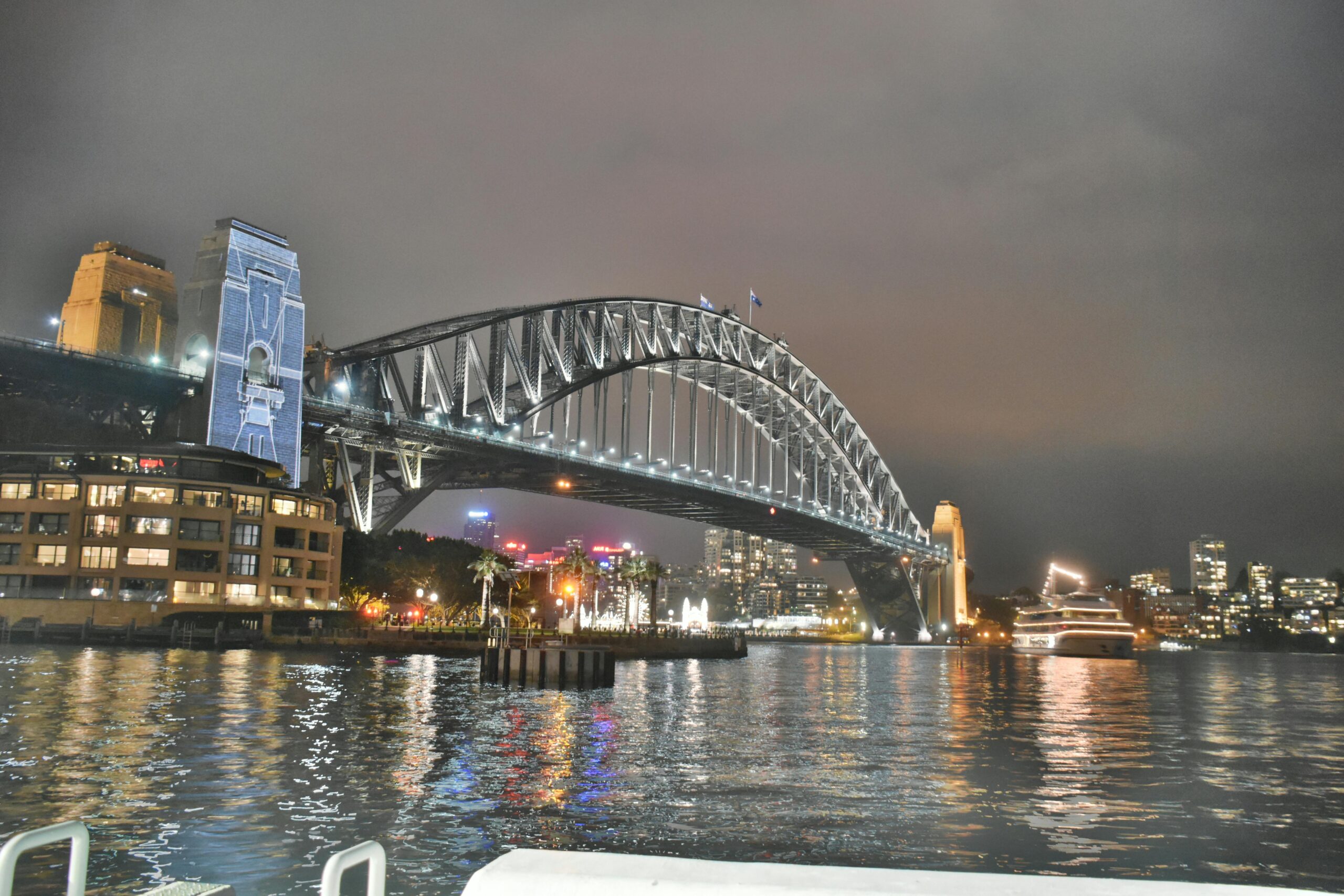Stunning night view of the illuminated Sydney Harbour Bridge reflecting in the water.
